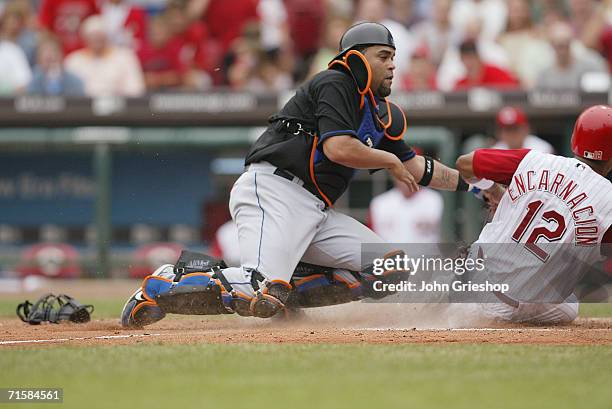 Edwin Encarnacion of the Cincinnati Reds slides toward Ramon Castro of the New York Mets during the game at Great American Ball Park in Cincinnati,...