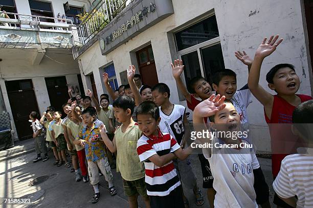 Boys from the West Point Training Center wave goodbye to elderly as a sign of respect after their visit to a home August 1, 2006 in Hangzhou,...