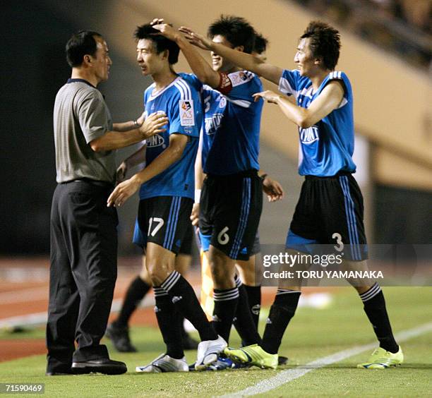 China's Dalian Shide FC forward Zou Jie is congratulated by teammates Zhang Yao Kun , Liu Cheng and coach Ling Le Feng on his goal against Japanese...