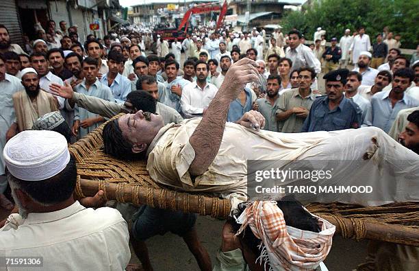 Pakistani rescuers carry the body of a man pulled from a river after a bridge collapsed in Mardan, some 50 kms northeast of Peshawar, 05 August 2006....