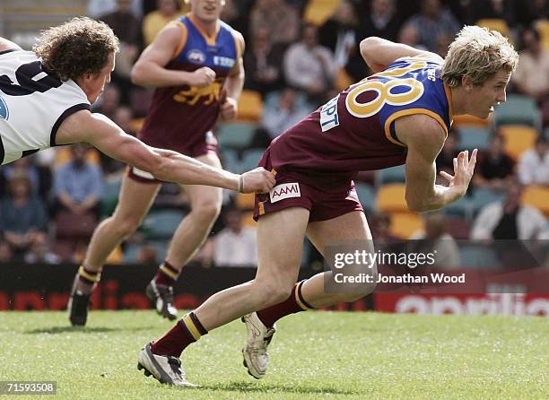 Troy Selwood of the Lions avoids the tackle James Kelly of the Cats during the round 18 AFL match between the Brisbane Lions and Geelong at the Gabba...