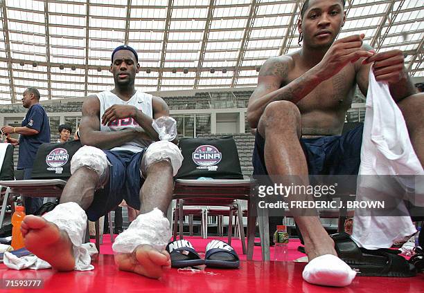 Stars LeBron James of the Cleveland Cavaliers receives ice-treatment on his knees and ankles while seated beside Carmelo Anthony of the Denver...