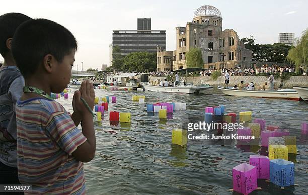 Young boy prays after releasing a floating lantern onto the Motoyasu river in front of the Atomic Bomb Dome for the victims of the bomb and for world...