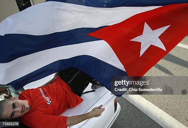 Nick Sabogal of Miami lays on his trunk while holding a Cuban flag along Calle Ocho in the Little Havana neighborhood August 7, 2006 in Miami,...