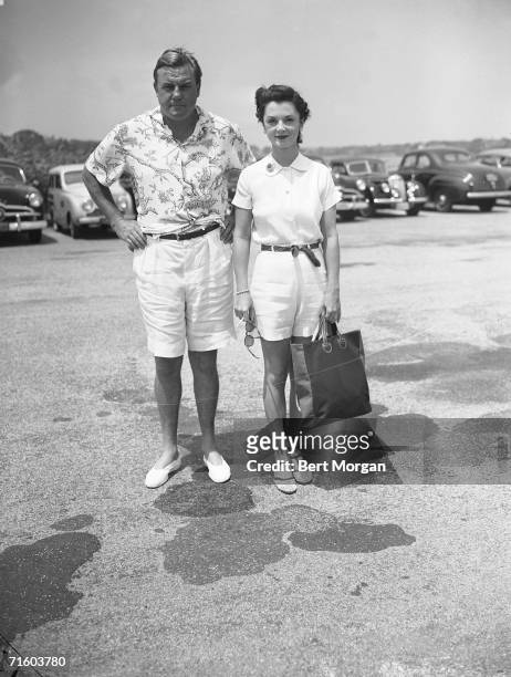 American professional football player John Sims Kelly and his wife debutante Brenda Frazier pose for a photograph in a parking lot as they wear their...