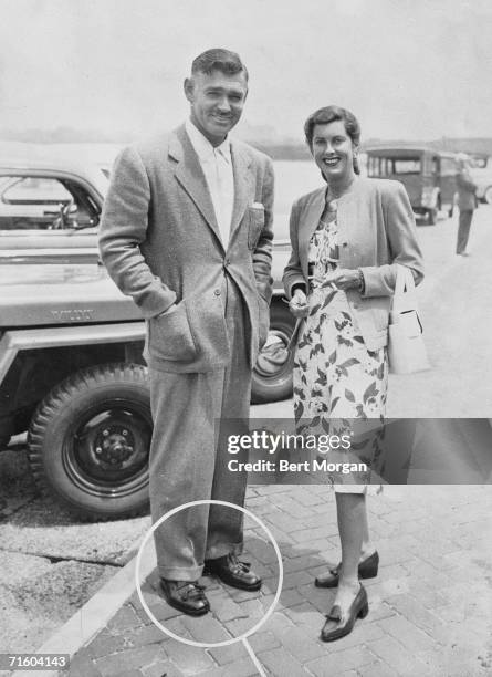 American actors Clark Gable and Sandra Shaw , wife of Gary Cooper, pause for a photograph next to a Willy's jeep in the parking lot of the...