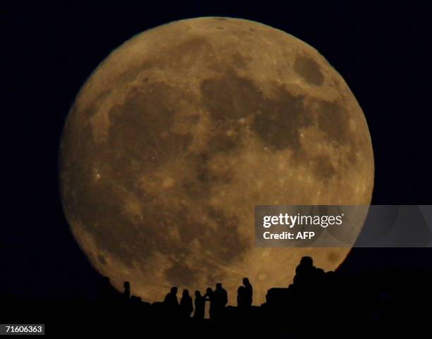 People admire the moon as it rises over cape Sounio, some 60 kilometers south of Athens, 08 August 2006. This year dozens of participating...