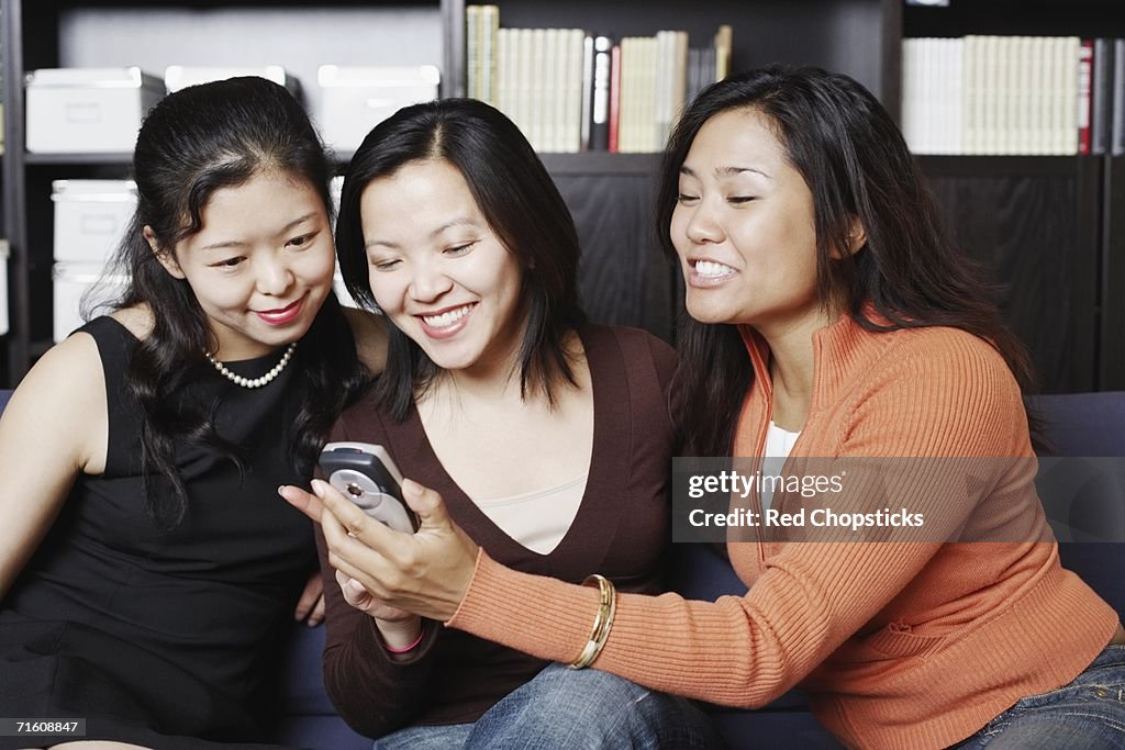 Close-up of three friends looking at a mobile phone smiling