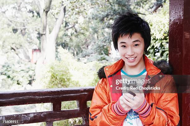 portrait of a teenage boy holding a mobile phone smiling - chinese collar stockfoto's en -beelden