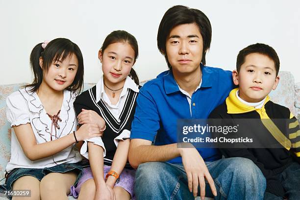 portrait of brothers and sisters sitting together - front view portrait of four children sitting on rock stock-fotos und bilder