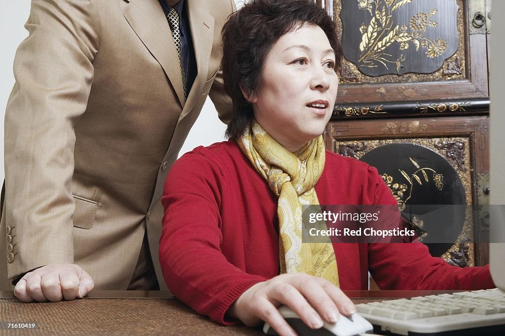 Close-up of a businesswoman using a computer with a businessman standing behind her