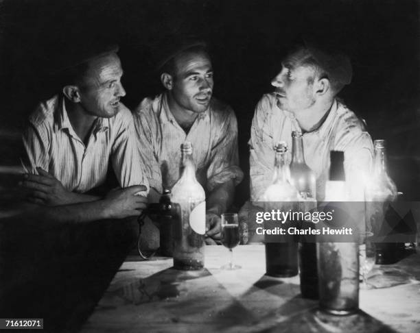 Three farm workers gather for a candlelit evening drink during the grape harvest in Jerez de la Frontera, home of sherry, 27th February 1954....