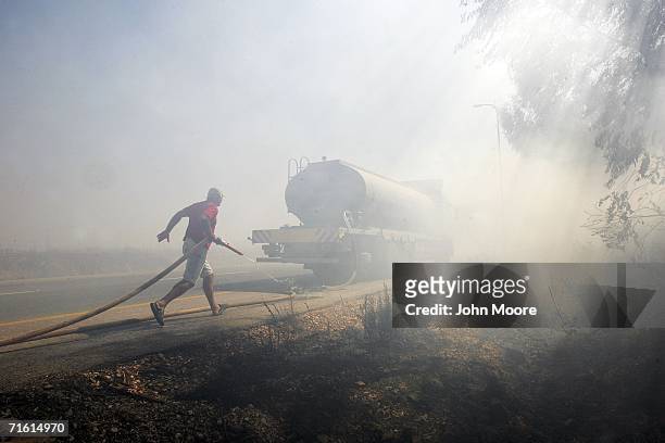 Fireman races to put out a brush fire set by a rocket fired by Hezbollah militants August 9, 2006 on Kiriat Shamona in northern Israel. Dozens of...