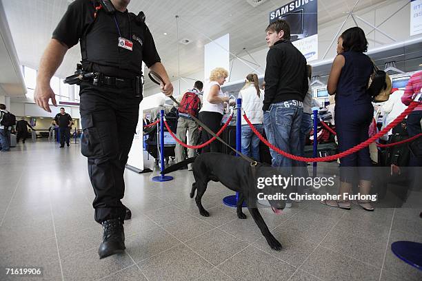 Poilce man and sniffer dog patrol the check in queues of Manchester Airport on August 10, 2006 in Manchester, England. British airports have been...