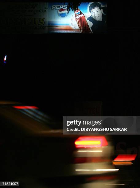 Indian commuters drive past a billboard featuring an image of cricketer Sachin Tendulkar and a cola advertisement in Bangalore, 10 August 2006.Indian...