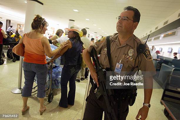 Miami-Dade police officer, Carlos Quintana, carries his weapon as he patrols the Miami International Airport August 10, 2006 in Miami, Florida. The...