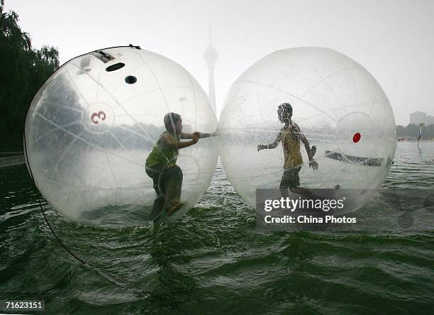 Boys play in water walking balls at Yuyuantan Park on August 10, 2006 in Beijing, China. The ball, that is 2.5 meters in diameter and filled with...