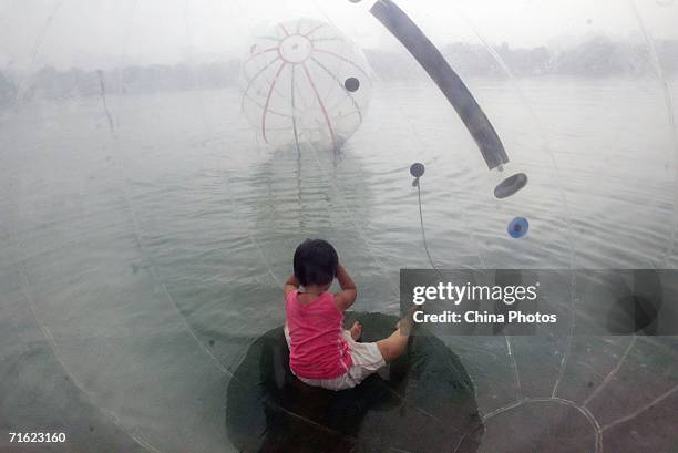 Girl sits in a water walking ball at Yuyuantan Park on August 10, 2006 in Beijing, China. The ball, that is 2.5 meters in diameter and filled with...