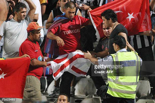 Greek Cypriot policeman asks Turkish Cypriot fans to put down the flag of the breakaway Turkish Republic of Northern Cyprus while others hold up a...