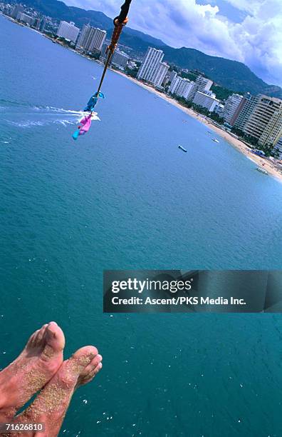 sandy feet of parasailor and high angle view of city, acapulco, mexico - drachenfliegen stock-fotos und bilder