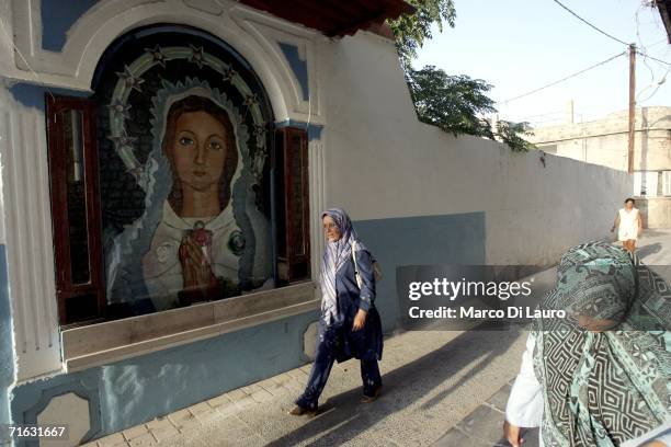 Two woman pass by a portrait of the Virgin Mary in a alley of a Christian neighborhood August 11, 2006 in Tyre, Southern Lebanon. An indefinite...