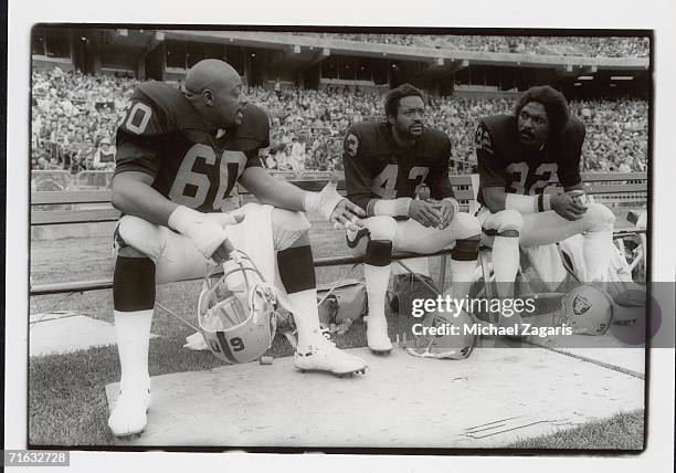 Defensive tackle Otis Sistrunk, safety George Atkinson and safety Jack Tatum of the Oakland Raiders sit on the bench during the game against the San...