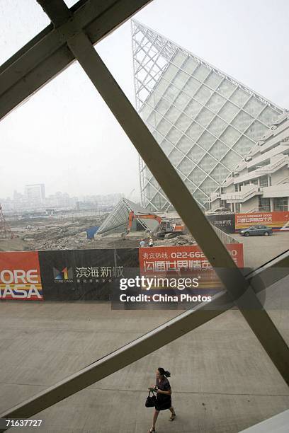 Woman walks past the Taida Resident Cultural Square under construction at Binhai New Area on August 12, 2006 in Tianjin Municipality, a megacity...
