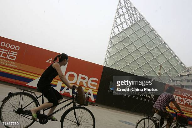 Women ride bikes past the Taida Resident Cultural Square under construction at Binhai New Area on August 12, 2006 in Tianjin Municipality, a megacity...