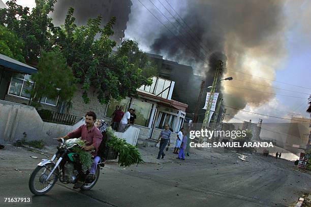 Lebanese civilians on a motorbike flee the area of an airstrike near a hospital in the southern port city of Tyre 13 August 2006. A huge fire from...