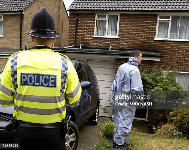 High Wycombe, UNITED KINGDOM: A British policeman looks 13 August 2006 at a police forensic expert outside a house in High Wycombe, which was raided...