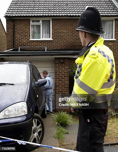 High Wycombe, UNITED KINGDOM: A British policeman watches a British police forensic expert outside a house in High Wycombe, southern England, 13...