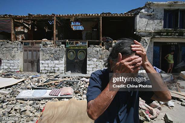 An elderly woman looks desperate as she stands in front of a house destroyed by typhoon Saomai at the Qianzhang Village on August 13, 2006 in Cangnan...
