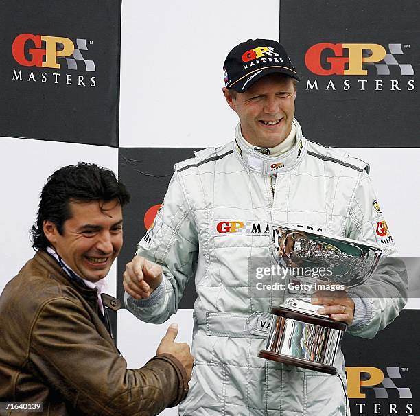 Eric van de Poele is handed the trophy by Jean Christophe Novelli after his second place in the GP Masters of Great Britain at Silverstone circuit on...