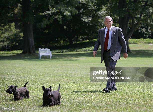 Washington, UNITED STATES: US President George W. Bush walks on the South Lawn with his dogs Barney and Miss Beazley upon return to the White House...