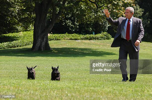 President George W. Bush waves as he arrives on the South Lawn of the White House with his dogs, Barney and Miss Beazley, August 13, 2006 in...