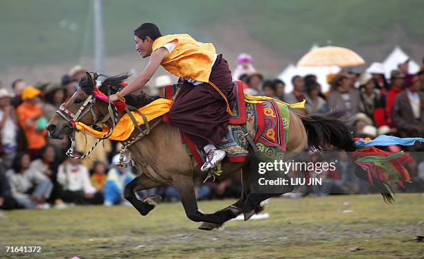 Tibetan lama shows off his equestrian skills during a performance as part of the annual Litang Horse Racing Festival in the wild west Tibetan county...