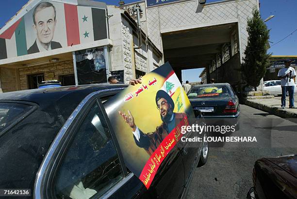 Lebanese citizens, waving portraits of Hezbollah leader Hassan Nasrallah, queue at the border point of Jdeidet Yabus, 40 kms west of Damascus, on...