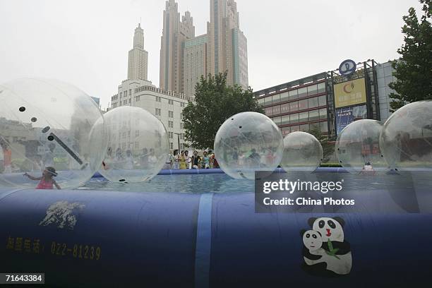 Children play in a water walking ball at a square on August 13, 2006 in downtown Tianjin Municipality, a megacity neighbouring Beijing, China. The...