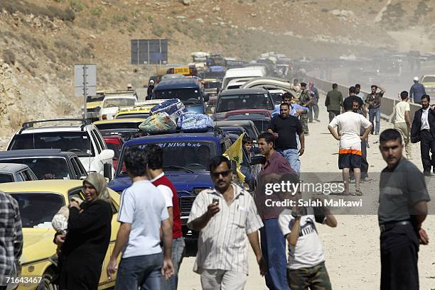 Lebanese refugees in Syria cross a big hole that cuts the international road between Lebanon and Syria on August 14, 2006 at the Lebanese checkpoint...