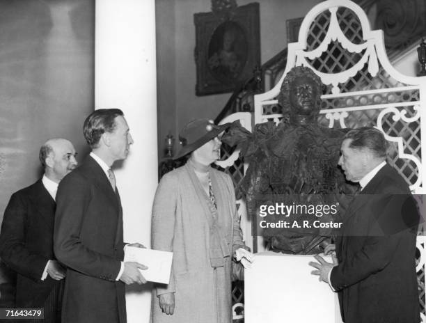 Lord Herbert, the former Crown Princess Cecilie of Prussia and M. Polovtsoff examine a bronze bust of Peter the Great at an exhibition of Russian art...