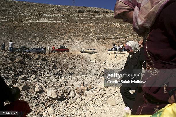 Lebanese refugees in Syria cross a crater that cuts the international road between Lebanon and Syria on August 14, 2006 at the Lebanese checkpoint of...