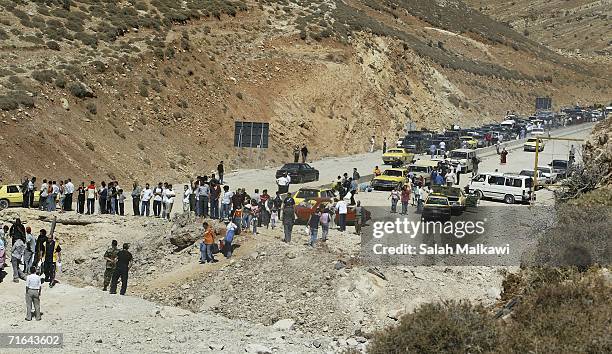 Lebanese refugees in Syria cross a crater that cuts the international road between Lebanon and Syria on August 14, 2006 at the Lebanese checkpoint of...