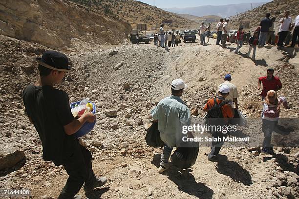 Lebanese refugees walk around a crater in the road as they travel between Syria and Lebanon on August 14, 2006 at the Lebanese checkpoint of...