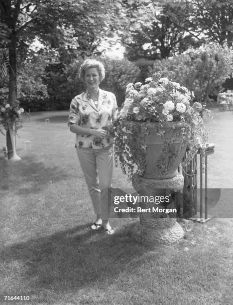 American socialite Charlotte Topping, wife of New York Yankees owner Dan Topping, stands by a large flowerpot on a pedestal in the garden at...