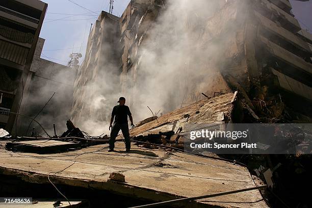 Man assists putting out a fire in neighborhood destroyed during the month long Israeli bombing campaign August 15, 2006 in southern Beirut, Lebanon....