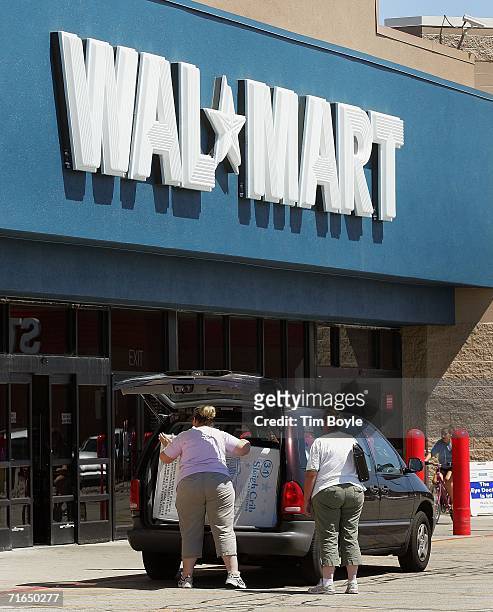 Shoppers load purchases into a van outside a Wal-Mart store August 15, 2006 in Mount Prospect, Illinois. Reportedly Wal-Mart profits fell 26 percent...