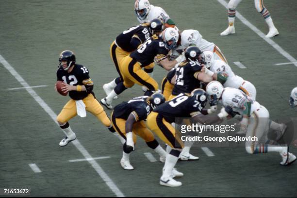 Quarterback Terry Bradshaw of the Pittsburgh Steelers drops back behind the blocking of offensive linemen Bennie Cunningham, Ted Petersen, Mike...
