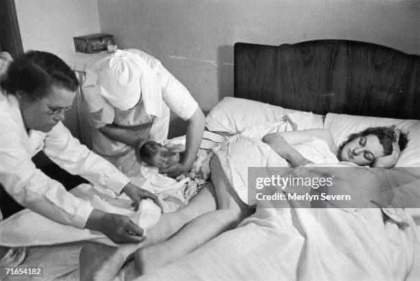 Midwife assists in a home birth in Mottingham, Kent, 4th August 1946. Mrs Lewington has just given birth to a baby daughter, Janet. Original...