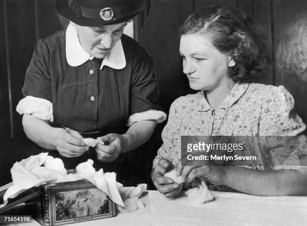 Midwife helps an expectant mother to pack a biscuit tin with gauze and cotton wool, after which it will be sterilised in the oven in preparation for...