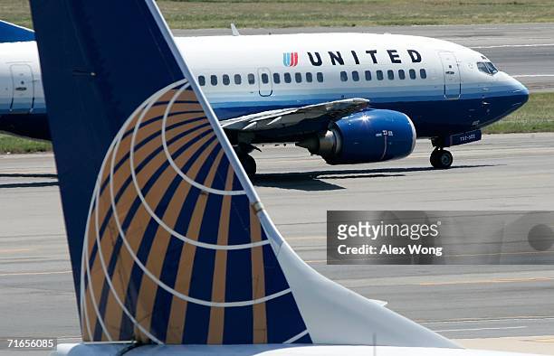 United Airlines aircraft passes by a Continental Airlines aircraft as it taxis to takeoff from the runway of Ronald Reagan National Airport August...
